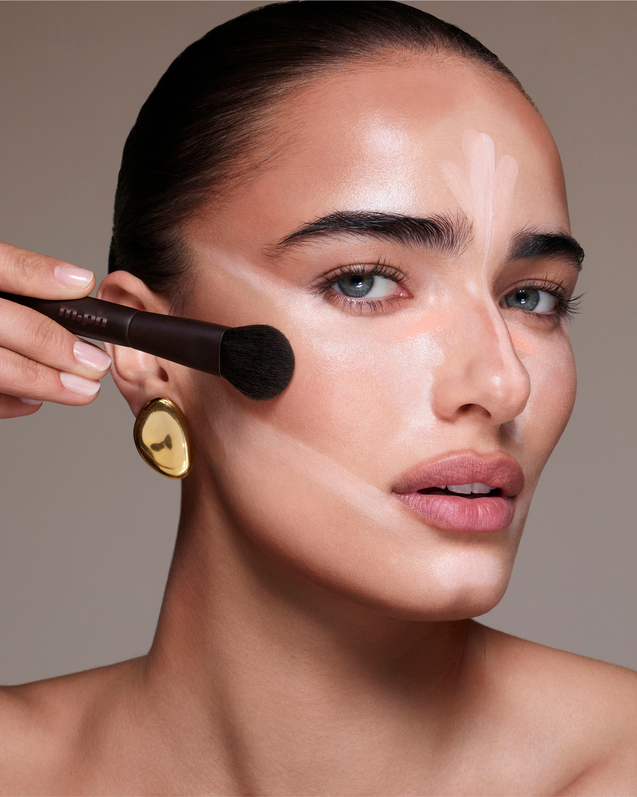 Person applying makeup with a brush on a neutral background