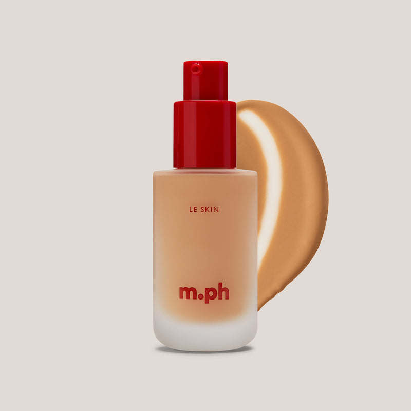 M.PH Le Skin light medium professional foundation in shade 170 with a golden-toned texture swatch behind the frosted glass bottle.