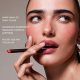 Woman applying lipstick with text about product features on a gray background