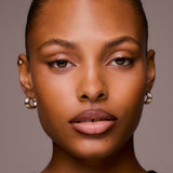 Close-up of a woman's face with gold hoop earrings against a neutral background